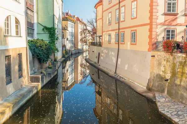 Rio entre casas antigas com flores com reflexão no outono — Fotografia de Stock