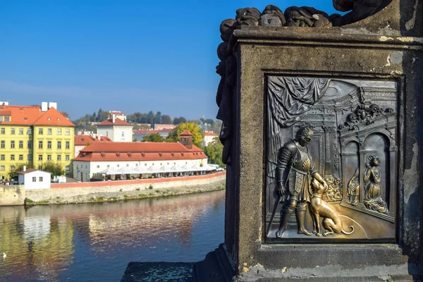 Metal engraving of a warrior with a dog with an old building on the background and river.