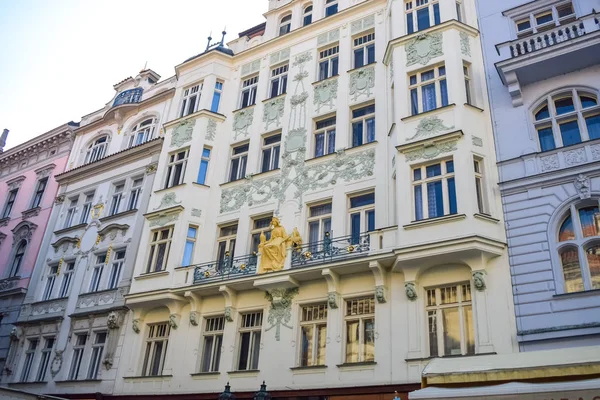 Fachada de un hermoso edificio antiguo con un adorno y una escultura dorada en Praga — Foto de Stock