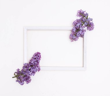 Beyaz arka planda beyaz ahşap çerçeve ve leylak çiçekleri. Metin ve model için boş alan.