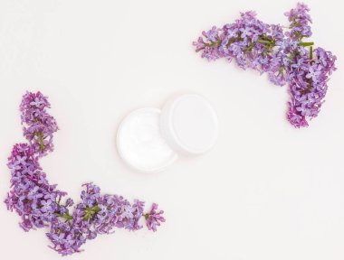 Beyaz arka planda krema ve leylak çiçekleri. Cilt bakımı, sağlık bakımı, kaplıca
