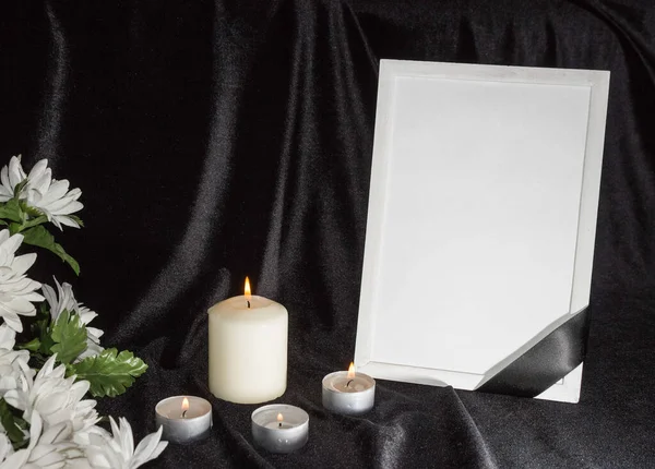 The concept of wake. Candles and white flowers on a black background. Funeral frame with free space and black funeral ribbon.