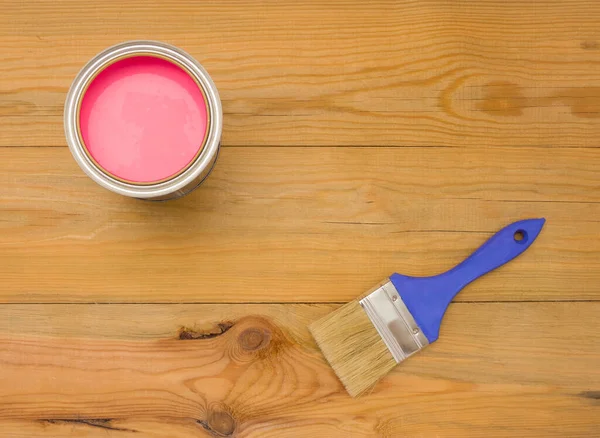 Tools for construction and decoration. Painting. A paintbrush and a metal can of paint. Wooden background, top view, copyspace.