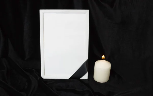 Condolence card. Memorial frame with black ribbon. White candle. Black background.