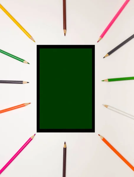 Background for school and student design. Colored pencils around a rectangle in the form of a blackboard. Free space for text. White background, top view.