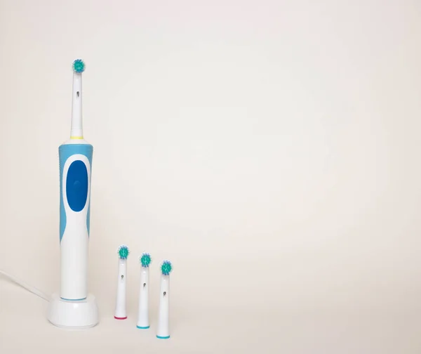 Ηλεκτρική οδοντόβουρτσα στο φορτιστή βάσης και αφαιρούμενα μέρη από αυτό σε λευκό φόντο. Ελεύθερος χώρος για κείμενο. — Φωτογραφία Αρχείου