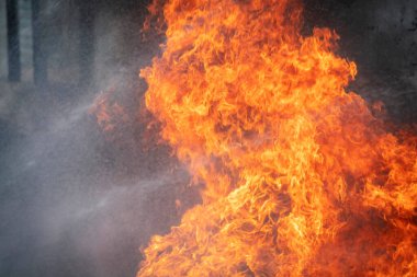 Yangın söndürücü ve su kullanan itfaiyeci, acil bir durumda yangın aleviyle mücadele eder. Tehlike anında bütün itfaiyeciler güvenlik için itfaiyeci kıyafeti giyer..