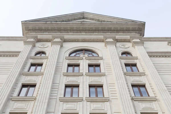 Perspective and symmetry in building. Vintage architecture classical facade with projection in Empire style. Front view close-up.