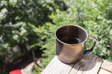 Eski ordu metal yanmış kupa ile bir çay. Bu bir woooden tahta üzerinde yer almaktadır. Arka plan bulanık.