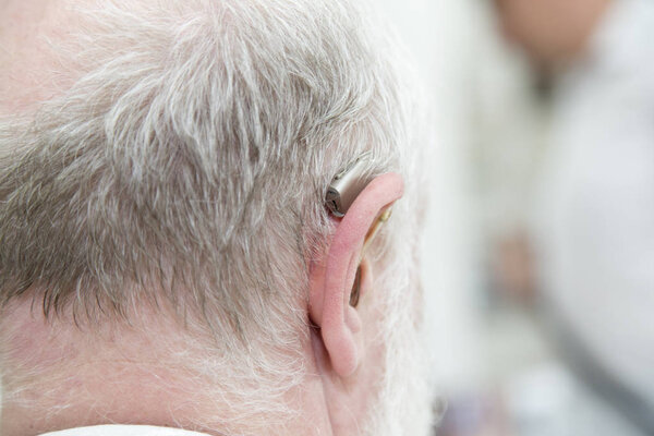 Голова старика с глухой помощью. Крупный план сзади
.