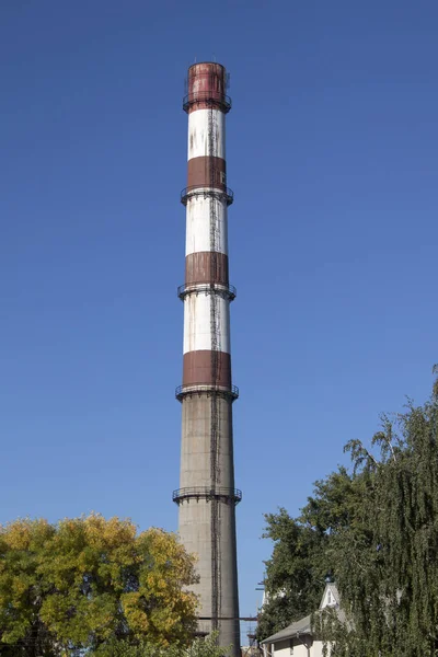 Stop a smoke stack. Let\'s make our world cleanest. There is vertical image with a smoke stack and the blue sky.