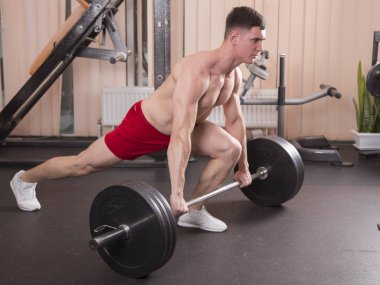 Genç adam kasları ile Halter salonunda esneme. Yakın çekim.