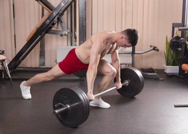 Genç adam kasları ile Halter salonunda esneme. Yakın çekim.