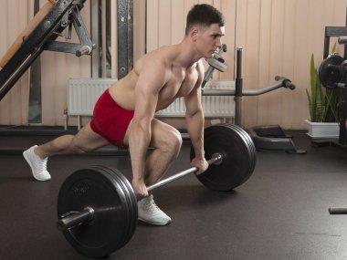 Genç adam kasları ile Halter salonunda esneme. Yakın çekim.