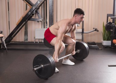 Genç adam kasları ile Halter salonunda esneme. Yakın çekim.