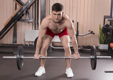 Genç adam kasları ile Halter salonunda esneme. Yakın çekim.