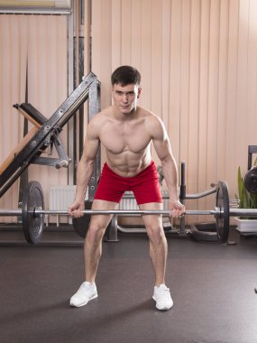 Genç adam kasları ile Halter salonunda esneme. Yakın çekim.