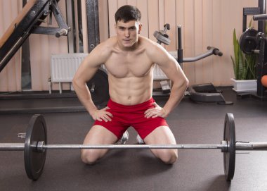 Genç adam kasları ile Halter salonunda esneme. Yakın çekim.