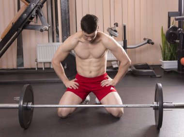 Genç adam kasları ile Halter salonunda esneme. Yakın çekim.