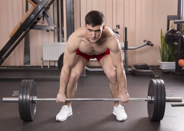 Genç adam kasları ile Halter salonunda esneme. Yakın çekim.