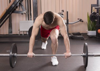 Genç adam kasları ile Halter salonunda esneme. Yakın çekim.