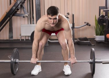 Genç adam kasları ile Halter salonunda esneme. Yakın çekim.