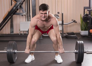 Genç adam kasları ile Halter salonunda esneme. Yakın çekim.