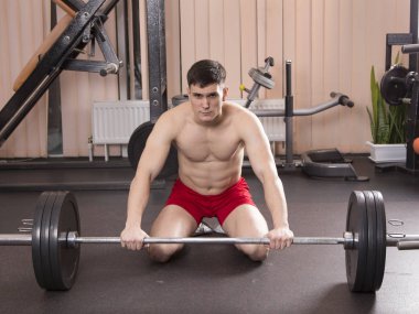 Genç adam kasları ile Halter salonunda esneme. Yakın çekim.