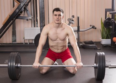 Genç adam kasları ile Halter salonunda esneme. Yakın çekim.