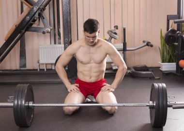 Genç adam kasları ile Halter salonunda esneme. Yakın çekim.