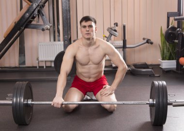 Genç adam kasları ile Halter salonunda esneme. Yakın çekim.