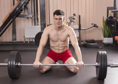 Genç adam kasları ile Halter salonunda esneme. Yakın çekim.