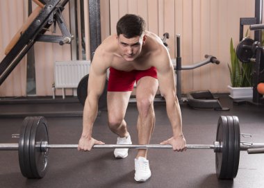 Genç adam kasları ile Halter salonunda esneme. Yakın çekim.