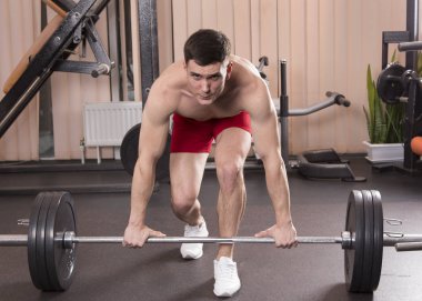 Genç adam kasları ile Halter salonunda esneme. Yakın çekim.