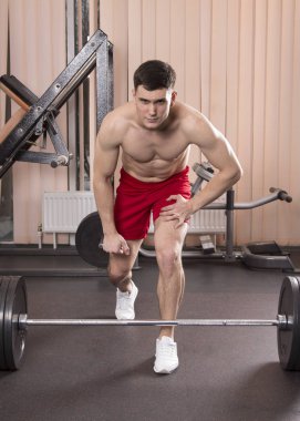 Genç adam kasları ile Halter salonunda esneme. Yakın çekim.