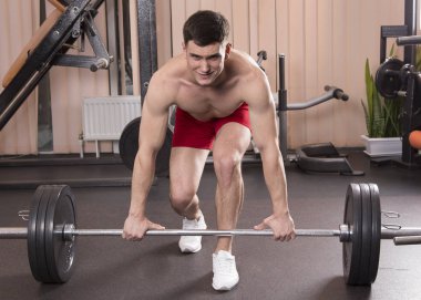 Genç adam kasları ile Halter salonunda esneme. Yakın çekim.