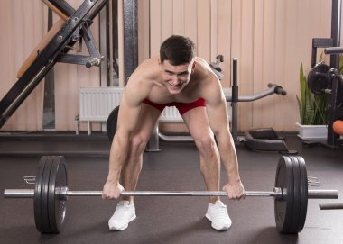 Genç adam kasları ile Halter salonunda esneme. Yakın çekim.