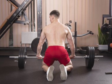 Genç adam kasları ile Halter salonunda esneme. Yakın çekim.