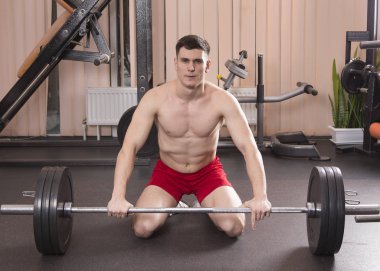 Genç adam kasları ile Halter salonunda esneme. Yakın çekim.