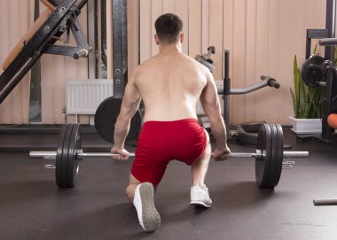 Genç adam kasları ile Halter salonunda esneme. Yakın çekim.