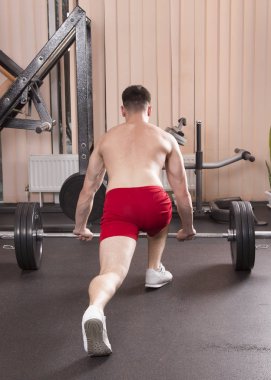 Genç adam kasları ile Halter salonunda esneme. Yakın çekim.