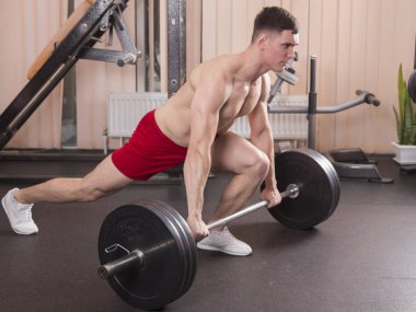 Genç adam kasları ile Halter salonunda esneme. Yakın çekim.