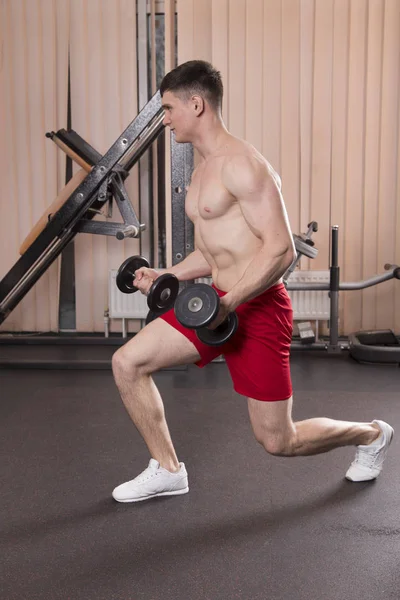Genç adam kasları ile Halter salonunda esneme. Yakın çekim.