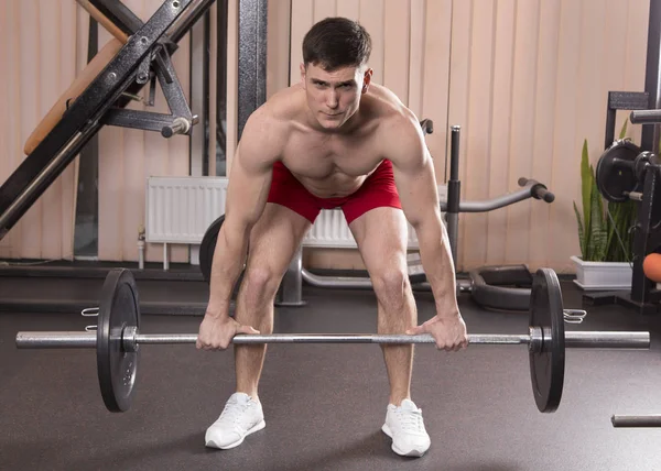Genç adam kasları ile Halter salonunda esneme. Yakın çekim.