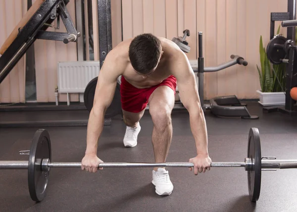 Genç adam kasları ile Halter salonunda esneme. Yakın çekim.