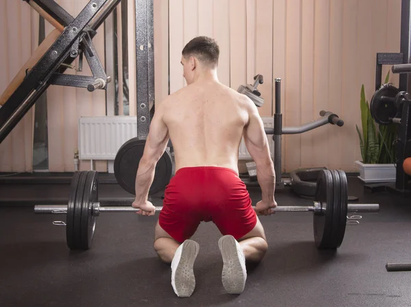 Genç adam kasları ile Halter salonunda esneme. Yakın çekim.