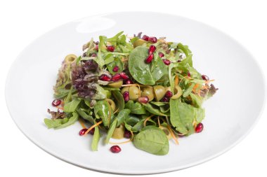 Beyaz tabak içinde ıspanak ve nar salatası.