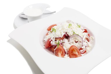 Beyaz tabakta domates ve peynir salatası.