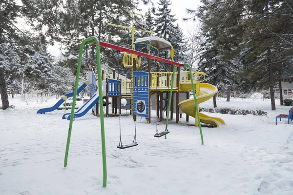 Parque infantil colorido é coberto de neve no inverno . — Fotografia de Stock