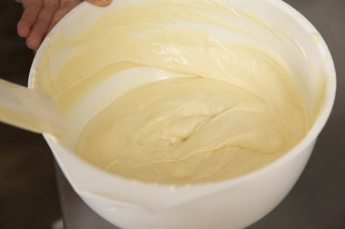 Bir kapta eritilmiş beyaz çikolata karıştırma.